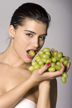 Part of photo series of a woman enjoying fresh green grapes. Studio shotの写真素材