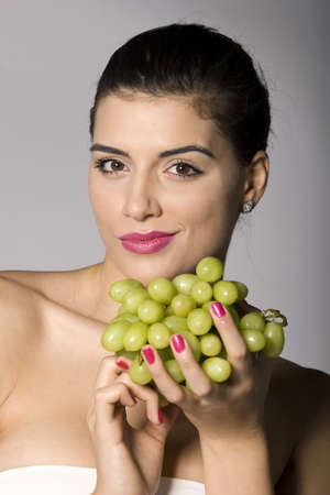 Part of photo series of a woman enjoying fresh green grapes. Studio shotの写真素材