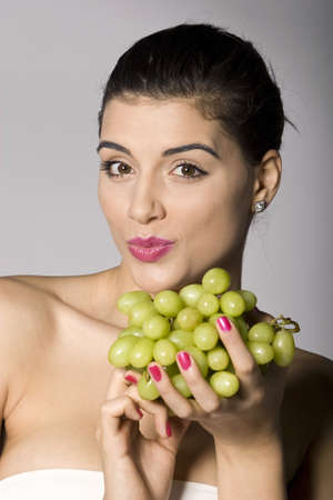 Part of photo series of a woman enjoying fresh green grapes. Studio shotの写真素材