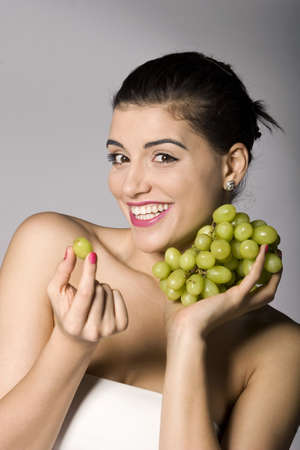Part of photo series of a woman enjoying fresh green grapes. Studio shotの写真素材