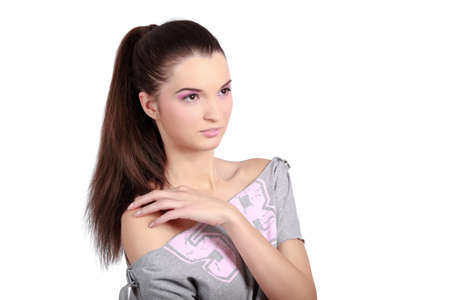 Beautiful young woman looking sideways and touching one shoulder. High resolution image taken in studio. Isolated on pure white background with copy space for your ad.の写真素材
