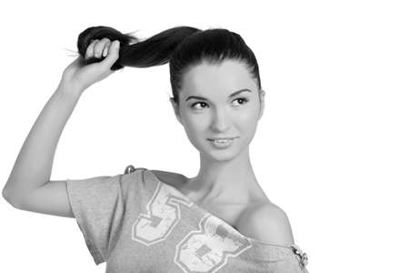 Beautiful young woman pulling her hair gently and smiling at the camera. High resolution monocrome image taken in studio. Isolated on pure white background with copy space for your ad.の写真素材