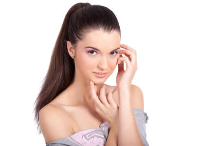 Portrait of a beautiful young woman with ponytale, touching her face  and looking at the camera. High resolution image taken in studio. Isolated on pure white background with copy space for your ad.の写真素材