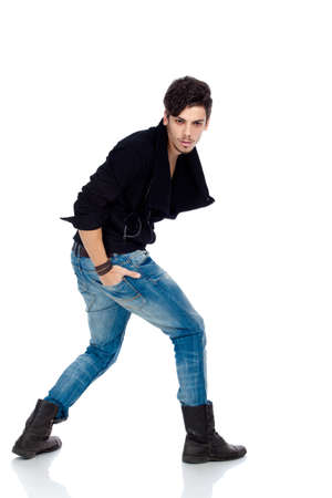 Handsome young fashion model wearing jeans, boots and a black jacket. Isolated on white background. Studio vertical image.の写真素材