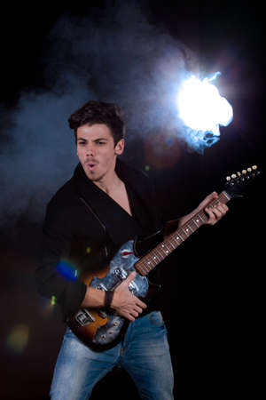 Concept for rock concert. Artistic image of young cool man  playing electric guitar. Image taken in studio with backlight and lens flare.の写真素材