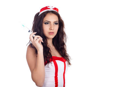 Portrait of a sexy young nurse with long curly hair holding a syringe on isolated white background. High resolution studio image with copy space for text.の写真素材
