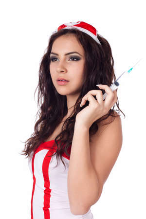 Vertical portrait of a sexy young nurse  with long curly hair holding a syringe and looking aside on isolated white background. High resolution studio image with copy space for text.の写真素材