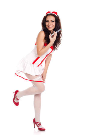 Full body shot of a sexy beautiful young nurse wearing red high heels shoes holding a syringe  and smiling on isolated white background. High resolution studio image with copy space for text.の写真素材