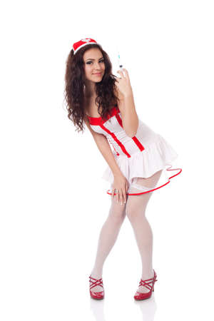 Full body shot of a sexy beautiful young nurse wearing red high heels shoes holding a syringe on isolated white background. High resolution studio image with copy space for text.の写真素材