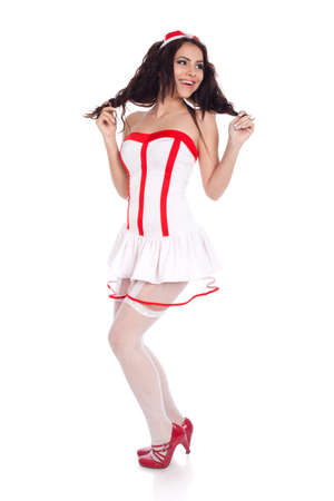 Full body shot of a happy sexy beautiful young nurse wearing red high heels shoes looking aside on isolated white background. High resolution studio image with copy space for text.の写真素材