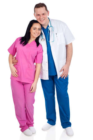 Young happy couple of handsome man doctor and pretty nurse in blue and pink scrubs uniforms, looking at camera. Full body image, isolated on white background. High resolution in studio, part of healthcare concept series.の写真素材