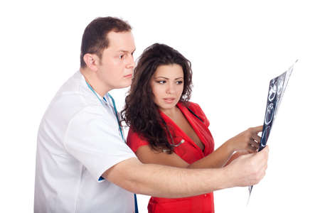 Young couple of handsome man doctor and pretty nurse in white and tangerine tango uniforms, interpreting a computed tomography (CT). High resolution image isolated on white background. Healthcare concept series.の写真素材