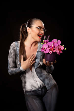 Happy sensual woman holding a purple flowers vase. She is naked, covered in business suit bodypainting. High resolution studio image on black background.の写真素材