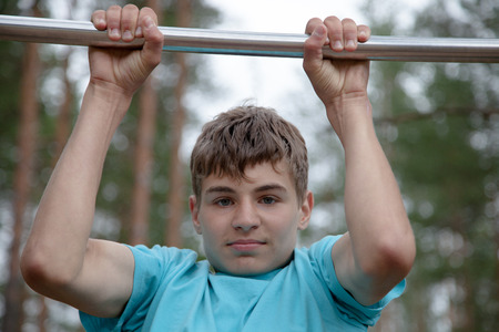 The teenager doing exercise on a horizontal barの写真素材