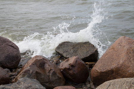 The waves breaking about stones and sprayの写真素材
