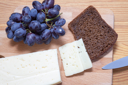 cheese, grapes and bread on the wooden tableの写真素材