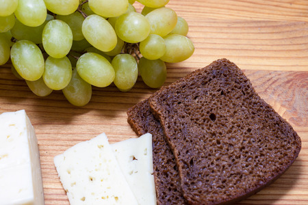 cheese, grapes and bread on the wooden tableの写真素材