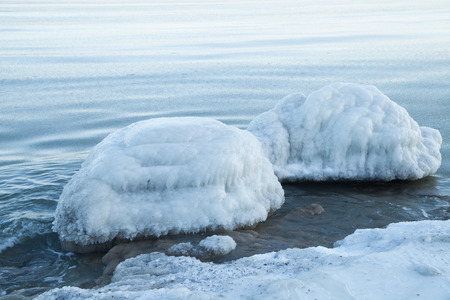 Stones covered with ice in the waterの写真素材