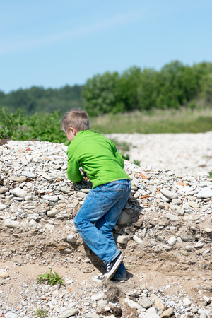 Young boy is playing near a streamの写真素材