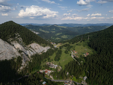 Aerial view of mountain village with forested slopes and green meadowsの写真素材