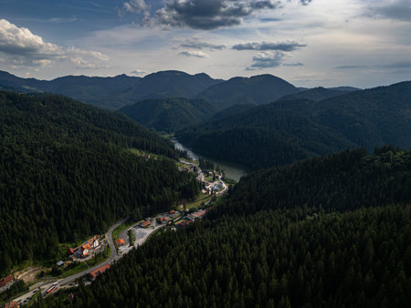 Aerial view of forest mountain valley with winding road and small villageの写真素材