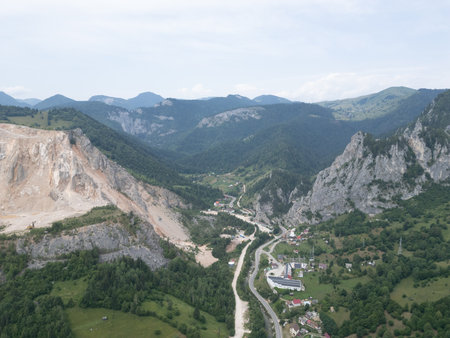 Aerial view of mountain valley with winding road and villageの写真素材
