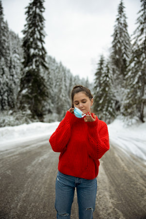 girl taking off protective neoprene face mask on the snowy roadの写真素材