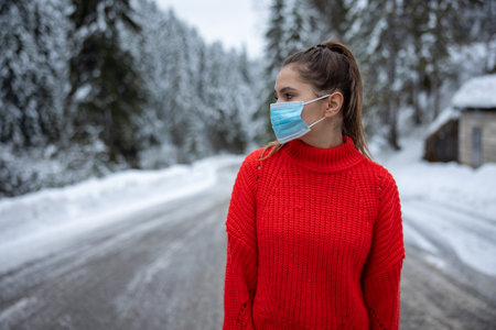 girl taking off protective neoprene face mask on the snowy roadの写真素材