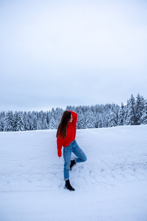 a girl in the snow with a red sweatshirt on a background of snow in the mountains coldの写真素材