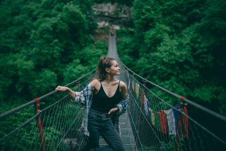 a girl in a black T-shirt on a Tibetan bridge wading sideways in search of adventureの写真素材