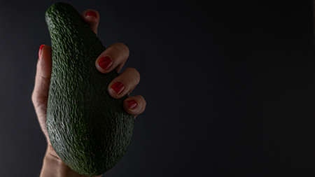 woman hand holding avocado Isolated on black backgroundの写真素材