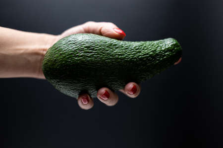woman hand holding avocado Isolated on black backgroundの写真素材