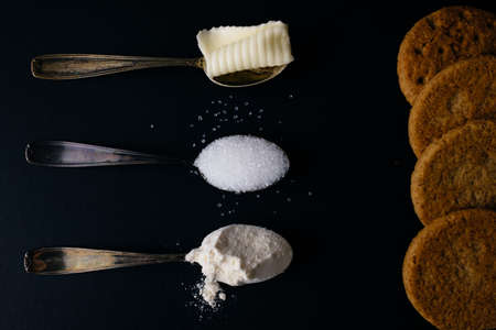 vintage silver spoons with sugar, butter and flour near the homemade cookiesの写真素材