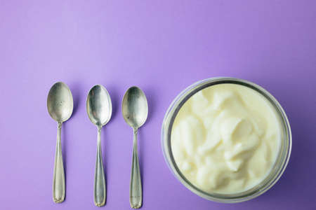jar of yogurt with a small silver spoonの写真素材