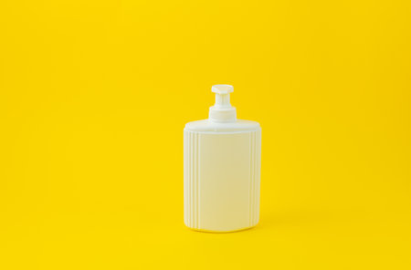 blank packaging white cosmetic cream pumping bottle isolated on yellow background ready for product designの写真素材