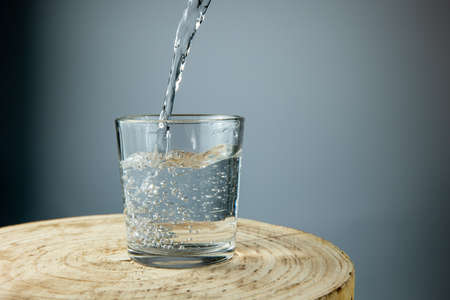 water pouring into glass on white background wooden tableの写真素材