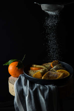 Pancakes. Thin pancakes. Russian bliny with orange and powdered sugar in the airの写真素材