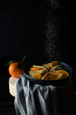 Pancakes. Thin pancakes. Russian bliny with orange and powdered sugar in the airの写真素材