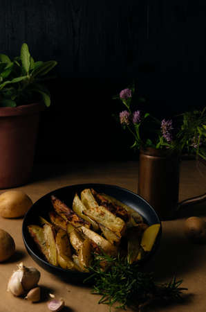 Potato wedges on dark background, cooking process. Process of making a rustic recipe of aromatic baked potatoes. food stylingの写真素材