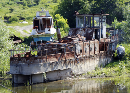 broken rusty ship standing on the river bankの写真素材