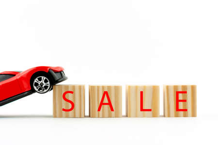 red car on a white background and wooden cubes with the inscription sale, car sale conceptの写真素材
