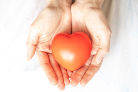 young beautiful and happy woman holding red cushion heart shape smiling isolated in white background