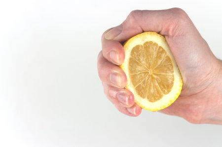 a woman's hand squeezes a lemon on a white