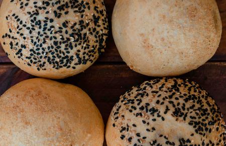 freshly baked buns with sesame seeds on a wooden background bought at a bakery,burger bunsの写真素材