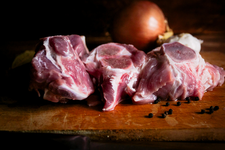 pork meat with bone on the table, garlic, black peppercornsの写真素材