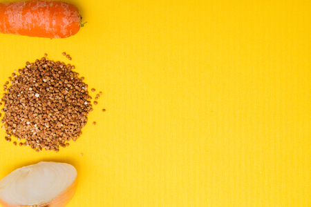 brown buckwheat beans, onion cut in half, carrots on a yellow backgroundの写真素材