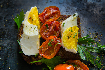 poached egg, boiled egg on toast with herbs and tomatoesの写真素材