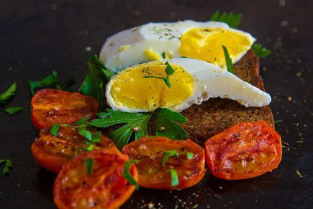 poached egg, boiled egg on toast with herbs and tomatoesの写真素材