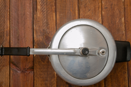 aluminum pressure cooker with black plastic handles on a wood backgroundの写真素材