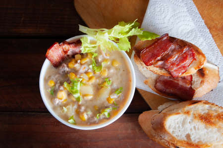 Corn chowder soup with bacon. Brown wooden background. Close-up viewの写真素材